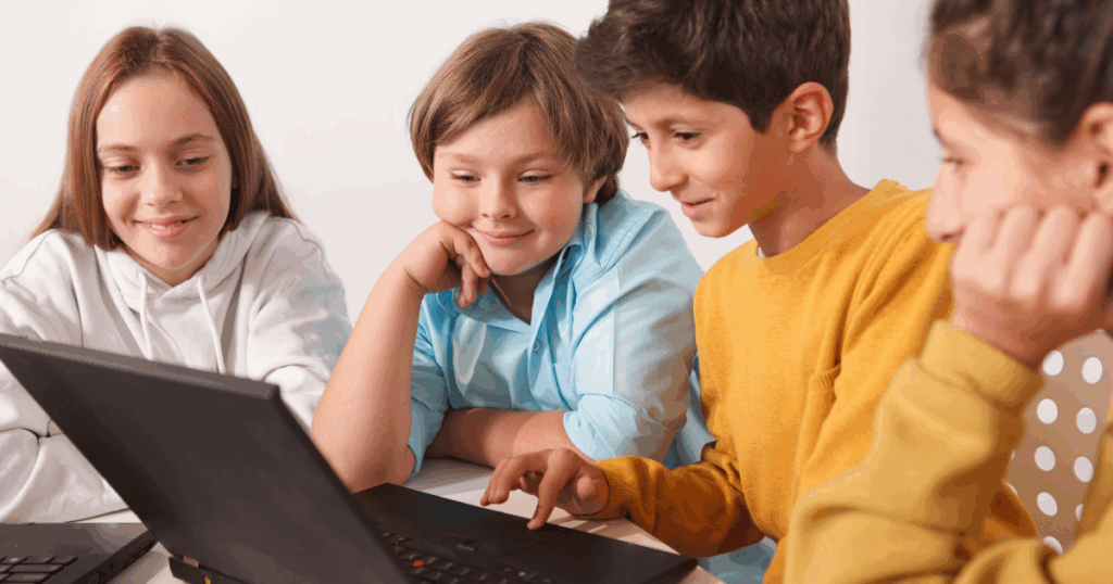 imagem ilustrativa de quatro crianças, sendo dois meninos e duas meninas ao redor de uma mesa com notebook no centro para acesso à plataforma educacional