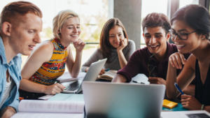 estudantes reunidos em grupo estudando com notebooks e materiais escolares