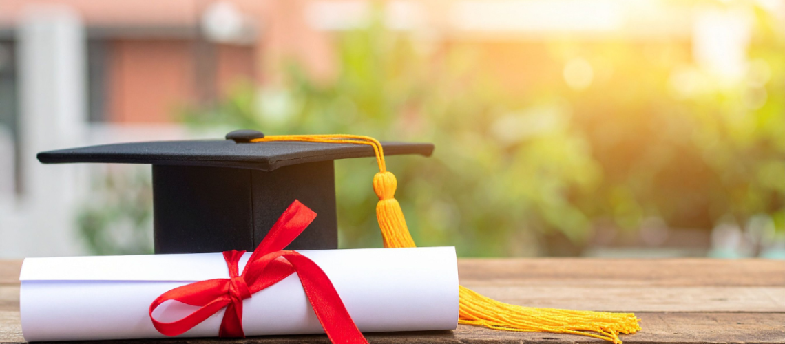high school diploma sobre uma mesa ao lado de um chapéu de formatura, representando a conclusão do ensino médio internacional