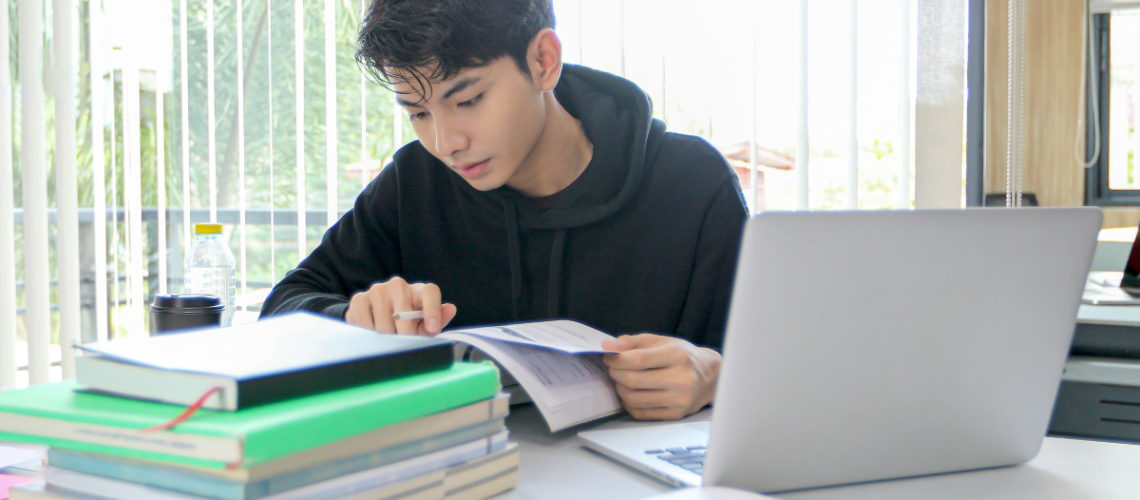 estudante organiza documentos e revisa materiais de estudo no computador enquanto se prepara para College Applications e universidades nos Estados Unidos