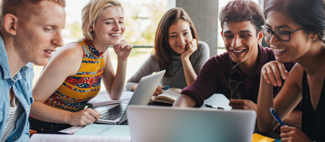 estudantes reunidos em grupo estudando com notebooks e materiais escolares