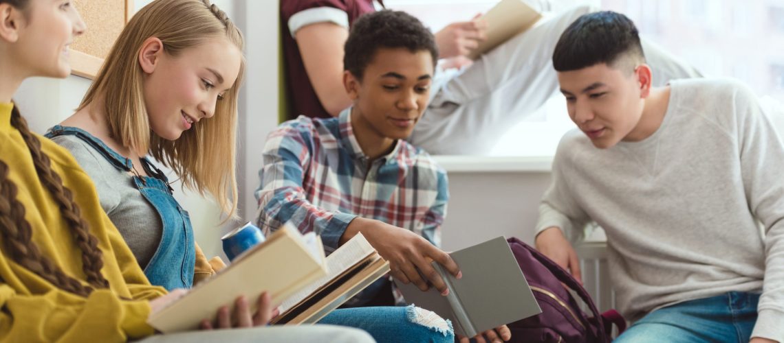 Group of multicultural high school teenage high school students doing homework during school break